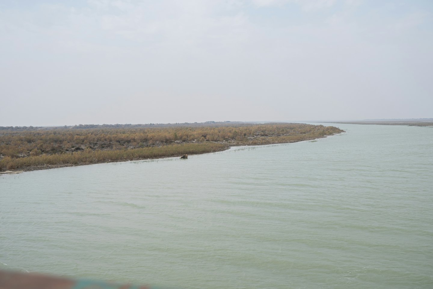A winding river flows through dry, overgrown land.
