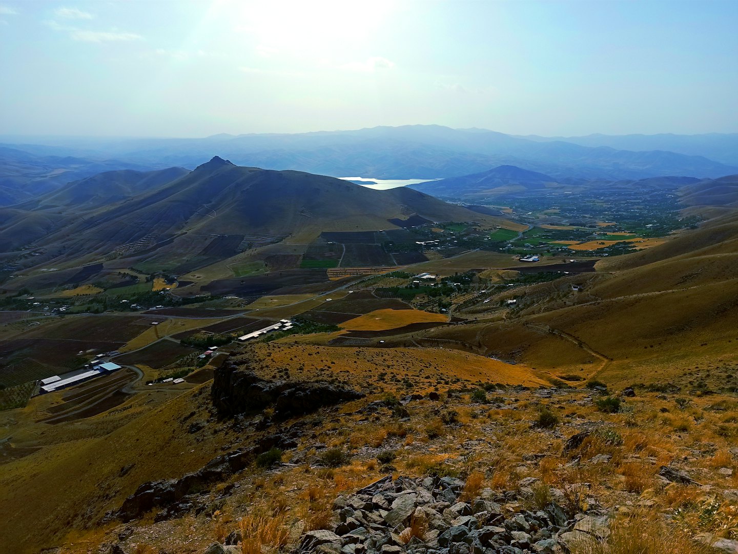 Rolling hills and agricultural fields stretch toward a distant lake.